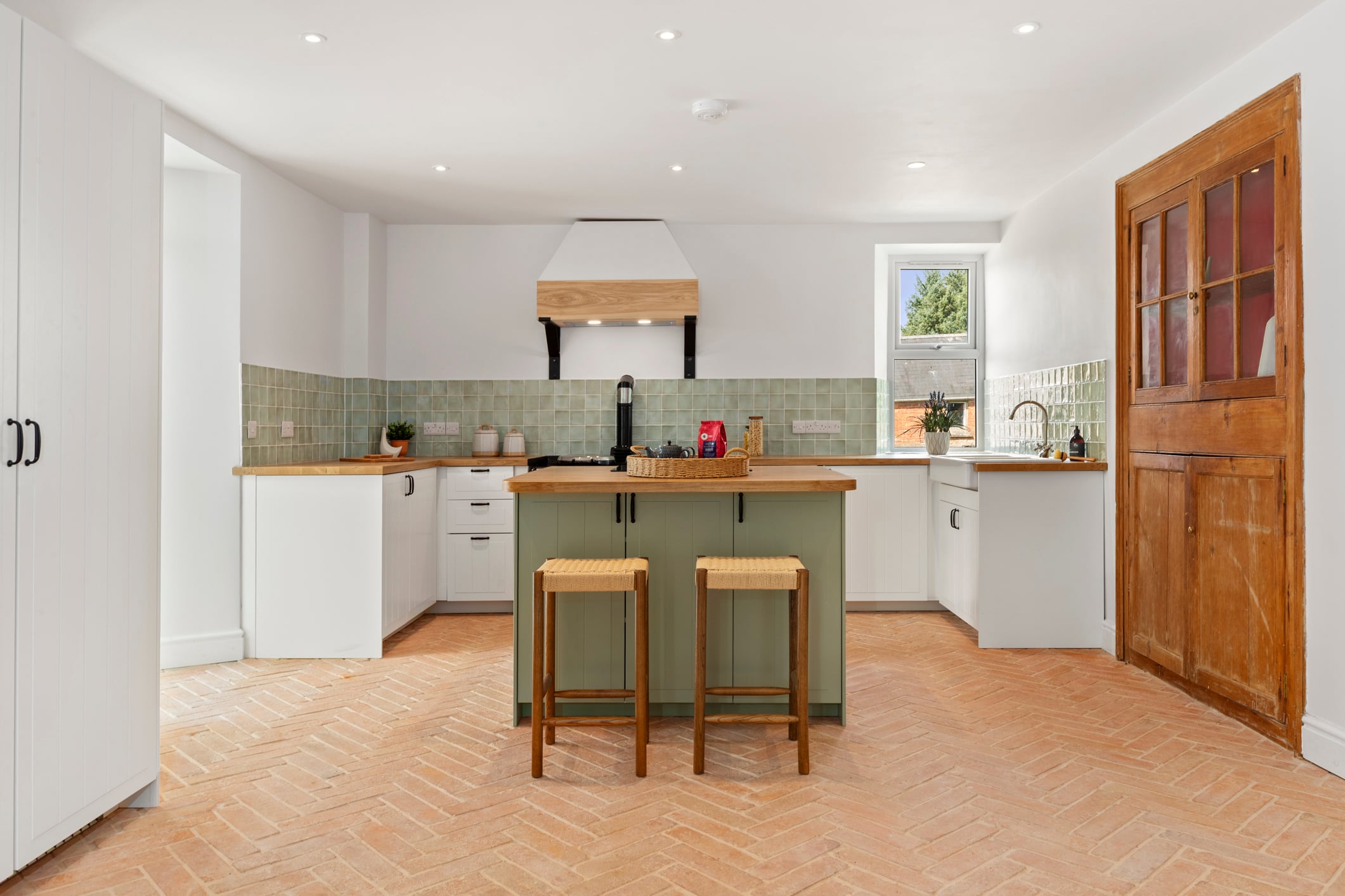 Kitchen with green island and oak door